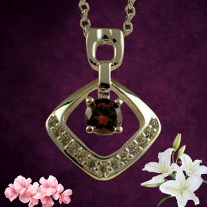 May include: Silver pendant necklace featuring a square-shaped frame with embedded small clear stones. A round, dark red gemstone is set in the center. The necklace is displayed against a dark purple background, with white flowers and pink flowers in the corners.