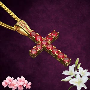 Könnte beinhalten: Eine goldfarbene Kreuz-Anhänger-Halskette mit roten Edelsteinen. Das Kreuz hängt an einer goldenen Kette. Der Hintergrund ist dunkelviolett. Rosa und weiße Blumen befinden sich in den Ecken.