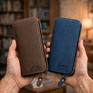 May include: Two rectangular zipped wallets, one in dark brown and one in navy blue. The brown wallet features a mountain graphic and the name LOTTE, while the blue wallet is personalised with the name Laurie Benton in a script font.