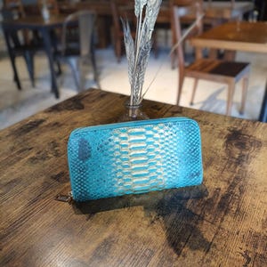 Puede incluir: Una taza de cerámica blanca con un asa negra y el texto "But First, Coffee" en negro, en negrita. La taza está sobre una superficie blanca.