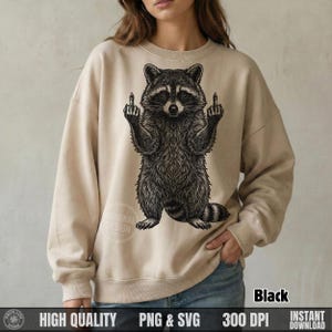 Woman wearing a beige sweatshirt with a solid black retro halftone sarcastic raccoon graphic