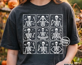 Może przedstawiać: Ciemnoszary t-shirt z białym nadrukiem graficznym przedstawiającym dziewięć kwadratów w ramkach, z których każdy ukazuje szkielet w innej pozie, w tym z rogami, z zakrytymi oczami oraz w pozycji lotosu, ozdobiony małymi kokardkami.