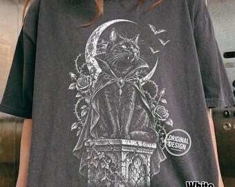Może przedstawiać: Ciemnoszary t-shirt z białym nadrukiem graficznym przedstawiającym czarnego kota w pelerynie wampira, siedzącego na kamiennym postumencie na tle półksiężyca, otoczonego różami, cierniami i nietoperzami, z napisem Original Design.