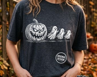 Może przedstawiać: Ciemnoszary melanżowy t-shirt z białą grafiką przedstawiającą dużą, groźną dynię z ostrymi zębami, za którą podążają trzy małe, uciekające duszki. Widoczna jest okrągła odznaka z napisem ORIGINAL DESIGN.