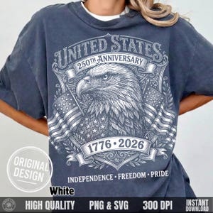 May include: A dark gray t-shirt featuring a detailed graphic commemorating the 250th anniversary of the United States. The design includes an eagle, American flags, and the text "UNITED STATES 250TH ANNIVERSARY 1776-2026". The shirt also has the words "INDEPENDENCE FREEDOM PRIDE".