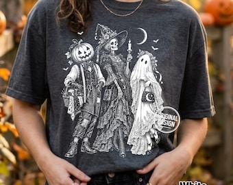 Może przedstawiać: Ciemnoszary t-shirt z białą grafiką przedstawiającą postać z głową dyni, szkielet w kapeluszu czarownicy oraz ducha w koronkowej zasłonie. Wzór zawiera również półksiężyc, małe nietoperze oraz okrągły stempel z napisem original design.