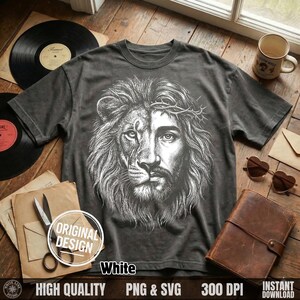 May include: Dark gray t-shirt featuring a detailed white graphic of a lion's face merged with Jesus' face, wearing a crown of thorns. The shirt has short sleeves and a crew neck. The words "White" and "Original Design" are also visible.