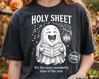 Może przedstawiać: Ciemnoszary t-shirt z białą grafiką śpiewającego ducha trzymającego śpiewnik. Tekst głosi HOLY SHEET oraz It's the most wonderful time of the year. Ducha otaczają nuty, płatki śniegu i wisząca latarnia.
