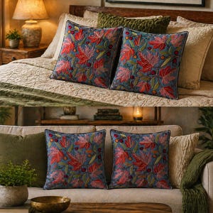 Könnte beinhalten: Zwei quadratische Kissen mit blauem Hintergrund und einem Muster aus roten und orangen Blättern und Beeren. Die Kissen befinden sich auf einem Bett und einem Sofa, mit anderen Kissen und Decken.