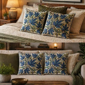 Könnte beinhalten: Zwei quadratische Zierkissen mit blauem Blättermuster auf cremefarbenem Hintergrund. Die Kissen befinden sich auf einem Bett und einem Sofa. Die Kissen haben einen dunkelblauen Rand und sind von anderen Kissen in neutralen Farben umgeben.