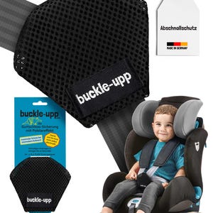 Può includere: Copertura per cintura di sicurezza per auto buckle-upp in rete nera con il nome del marchio su un'etichetta nera. Un bambino è seduto in un seggiolino auto con la copertura buckle-upp in posizione. È visibile anche una confezione del prodotto.