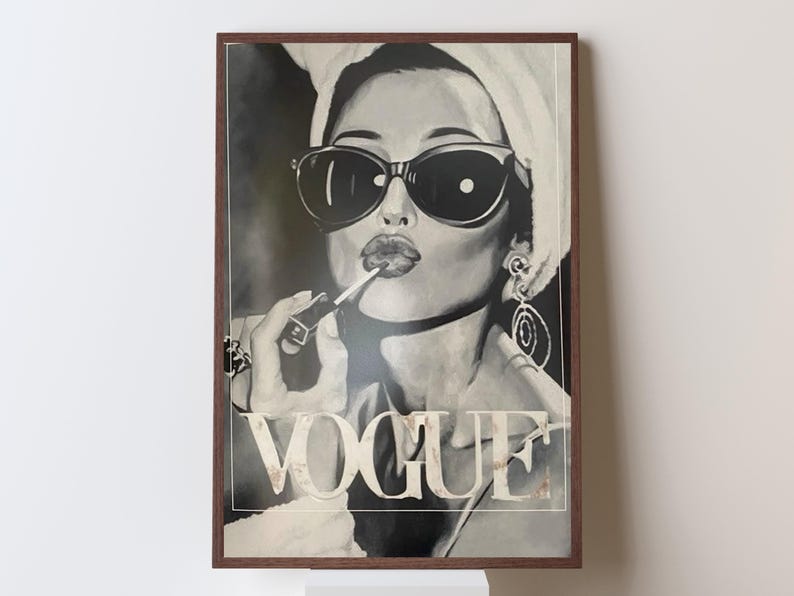 May include: Black and white framed print of a woman applying lipstick, wearing sunglasses and a towel on her head. The word "VOGUE" is displayed in large letters at the bottom of the image. The artwork has a vintage, glamorous aesthetic.