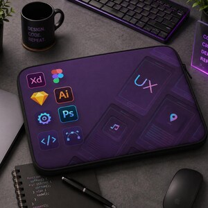 May include: A rectangular dark purple laptop sleeve featuring a graphic print of various software application icons, including Adobe XD, Illustrator, Photoshop, and a prominent UX label, alongside stylized mobile interface outlines on the surface.