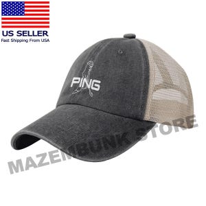 May include: A charcoal gray baseball cap with a mesh back. The cap features the PING logo embroidered in white on the front. The brim is curved, and the cap has an adjustable strap.