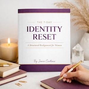 May include: A hardcover book titled "IDENTITY RESET" with a purple and gold design. The book is open, with a hand holding a gold pen. A lit candle, other books, and decorative items are also in the image.
