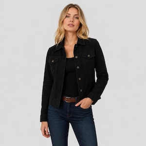 May include: A black jacket with a collared neckline, long sleeves, and a button-down front. The jacket features two chest pockets with buttoned flaps, dark blue denim jeans, and a brown leather belt with a silver-toned metal buckle.
