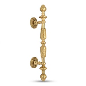 May include: A gold-colored door pull with ornate floral and leaf detailing. The handle features a vertical design with decorative finials at the top and bottom. The pull is approximately 12 inches in length.