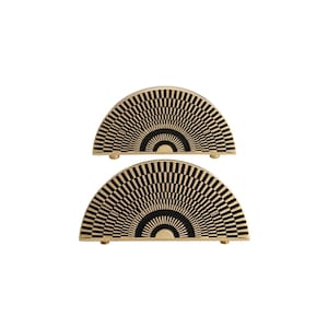 May include: Two half-circle decorative wooden pieces with a black and beige geometric pattern. Each piece has a series of black lines radiating from a central curved black area. The pieces are on small, round, wooden feet.