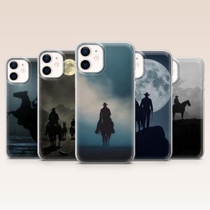 May include: Five clear phone cases arranged in a row, each featuring a different dark, atmospheric graphic of a cowboy on horseback. The designs include silhouettes of riders against large full moons, misty landscapes, and cloudy, moody night skies.