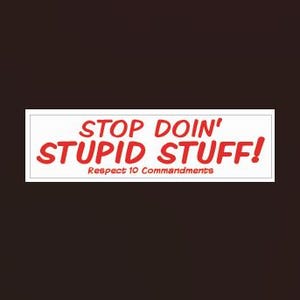 May include: A white rectangular bumper sticker with the text "STOP DOIN' STUPID STUFF!" in red, bold, and stylized font. Below, smaller red text reads "Respect 10 Commandments". The background is a dark brown.