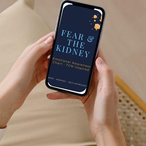 Puede incluir: Un teléfono inteligente muestra el texto "FEAR & THE KIDNEY" con "Emotional Awareness Chart - TCM inspired" debajo. El teléfono está sostenido por manos, sobre un fondo beige. El texto "BODY - EMOTION - SELF-KNOWLEDGE" está en la parte inferior de la pantalla.