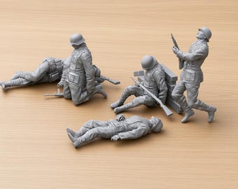 Peut inclure: Un ensemble de cinq figurines de soldats en plastique gris non peintes dans diverses postures de combat. Un soldat est allongé, un est à genoux, un est assis contre un mur de briques, un est debout avec un fusil et un est étendu au sol.