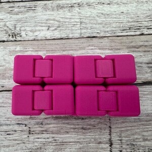 May include: A bright magenta infinity cube fidget toy composed of eight interconnected blocks. The device features a smooth, matte finish and a hinged design that allows the individual segments to fold and rotate into various geometric configurations.