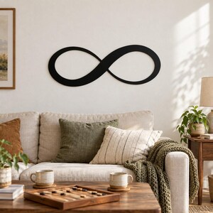 Puede incluir: Una pieza de arte mural con el símbolo de infinito en negro mate que presenta un diseño de bucle continuo, suave y fluido. El objeto tiene forma de ocho horizontal, caracterizado por sus líneas limpias, sólidas y su forma simétrica.
