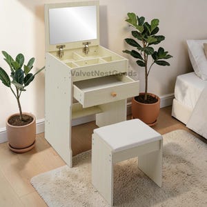 May include: A cream-colored vanity set with a flip-up mirror, multiple storage compartments, and a pull-out drawer. Includes a matching stool with a white cushioned seat. The set is made of wood and has a light, natural finish.