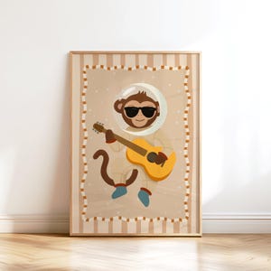 Peut inclure: Illustration encadrée d'un singe de dessin animé en combinaison spatiale, portant des lunettes de soleil et jouant d'une guitare jaune. L'œuvre a un fond beige avec une bordure rayée et un cadre en bois. Le singe est brun et la guitare a des détails bruns et orange.