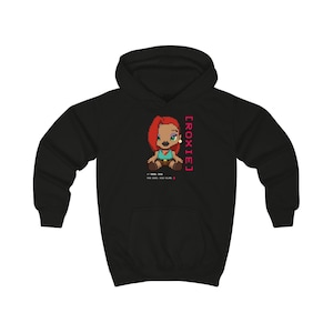 Puede incluir: Sudadera con capucha negra con un personaje de dibujos animados pixelado con cabello rojo y el nombre "ROXIE" en rosa. Texto adicional debajo del personaje. Una sudadera con capucha clásica y cómoda.