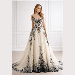 Vestido de novia gótico de corte A en tul color marfil, apliques florales negros bordados, escote redondo, ideal para una romántica recepción de boda gótica.