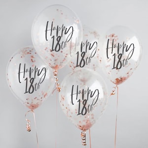 May include: Five clear balloons filled with rose gold confetti. Each balloon has the words "Happy 18th" printed in black script. The balloons are tied with rose gold ribbons.