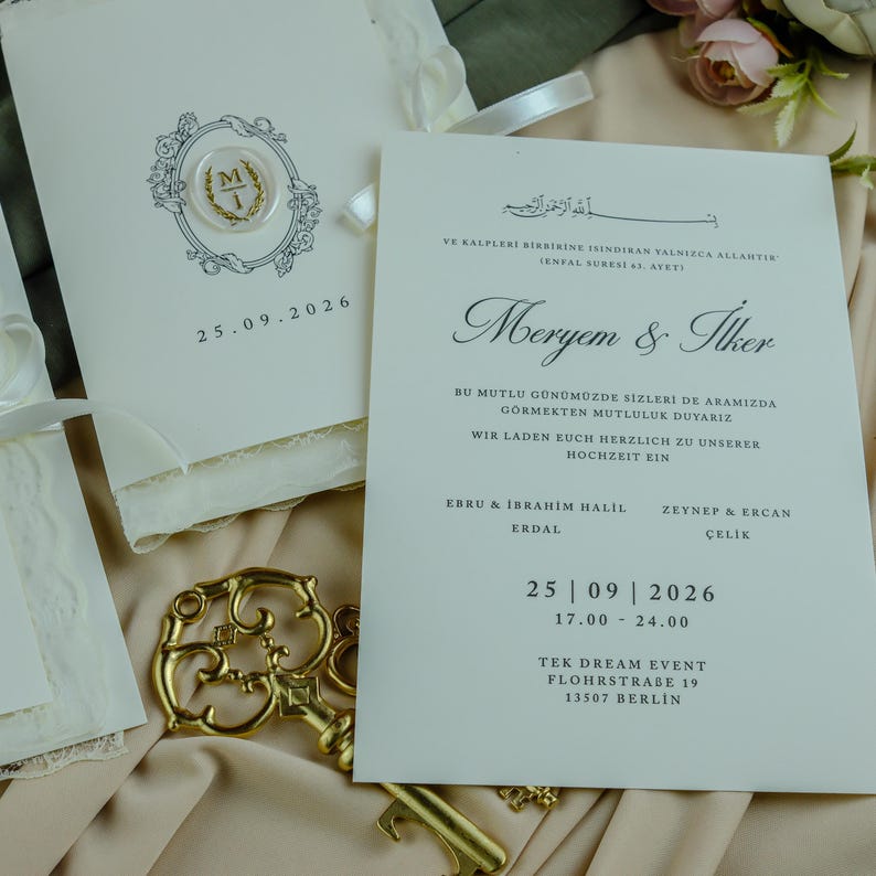 K&ouml;nnte beinhalten: Cremefarbenes Hochzeitseinladungs-Set mit einem goldenen Wachssiegel mit den Initialen MI, dem Datum 25.09.2026, schwarzem Text mit den Namen Meryem & Ilker, Veranstaltungsdetails f&uuml;r Berlin und einem dekorativen goldenen Skelettschl&uuml;ssel aus Metall.