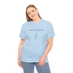 May include: Pale blue t-shirt featuring the phrase "don't trip the crip" and a stick figure design. This casual top is made from a soft fabric, ideal for everyday wear.