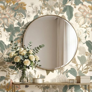 May include: A round, gold-framed mirror hangs on a wall with floral wallpaper. A glass vase with white roses and greenery sits on a gold metal console table. Decorative boxes are also on the table.