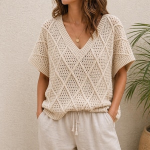 Peut inclure: Haut en crochet crème à manches courtes et col en V, orné d'un motif en losanges. Il est associé à un pantalon en lin clair. L'ensemble dégage une ambiance décontractée, idéale pour les journées chaudes.