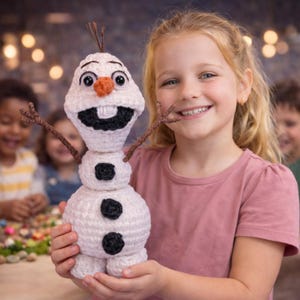 May include: A handmade crochet Olaf snowman doll with a carrot nose, twig arms, and black coal buttons. The snowman is held by a smiling child. The snowman is a character from the Disney film Frozen.