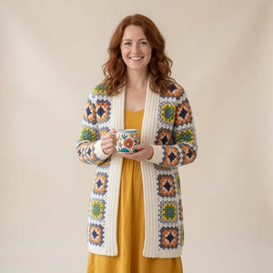 May include: A long-sleeved cardigan made of multi-colored granny squares in shades of blue, orange, green, and white, featuring a solid cream-colored ribbed trim along the front opening and cuffs, worn over a solid mustard yellow dress.