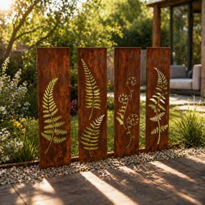 May include: Four weathered metal garden panels with fern leaf cutouts. The panels are a rusty brown color and are arranged in a row. The fern designs are a lighter gold color. The panels are set in a garden with a wooden deck.