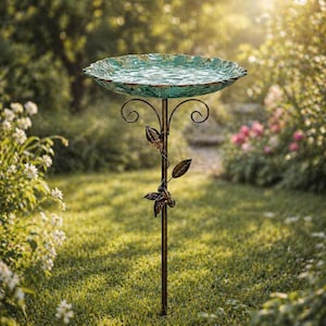 Könnte beinhalten: Ein dekoratives Vogelbad mit einer wellenförmigen Schale in Türkis. Die Schale steht auf einem bronzefarbenen Metallständer mit Blattakzenten. Das Vogelbad befindet sich in einem Garten mit grünem Gras und blühenden Pflanzen.