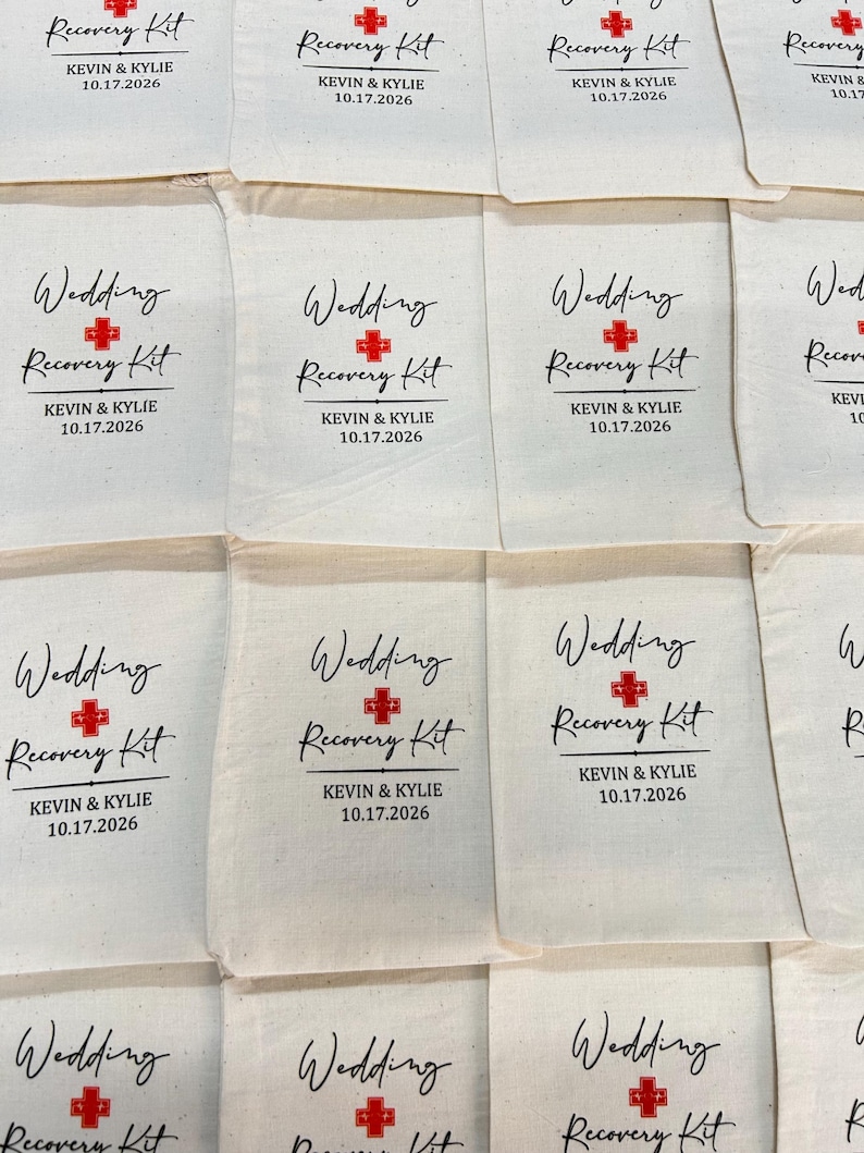 Puede incluir: Bolsas de tela color crema con la inscripci&oacute;n "Wedding Recovery Kit" en escritura negra, un s&iacute;mbolo de cruz roja y los nombres "KEVIN & KYLIE" con la fecha "10.17.2026". Se ven varias bolsas.