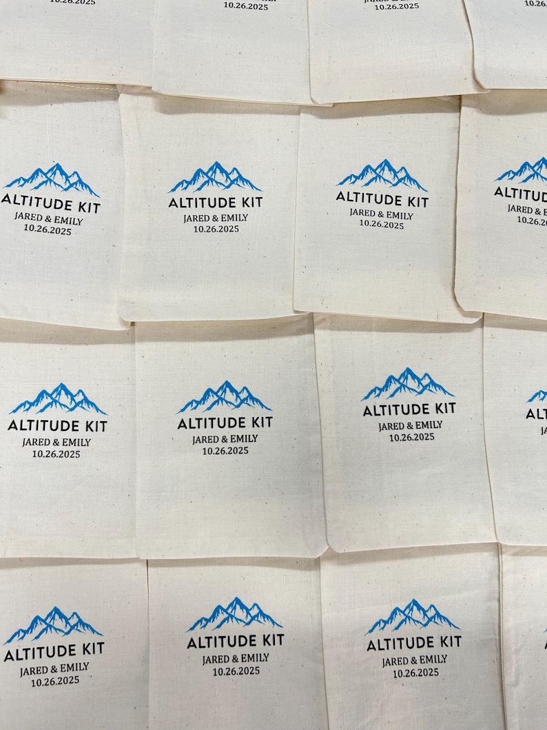 Puede incluir: Bolsas de tela blanquecina con un gr&aacute;fico de monta&ntilde;a azul y el texto "ALTITUDE KIT JARED & EMILY 10.26.2025". Las bolsas est&aacute;n dispuestas en un patr&oacute;n de cuadr&iacute;cula. El dise&ntilde;o se repite en varias bolsas.