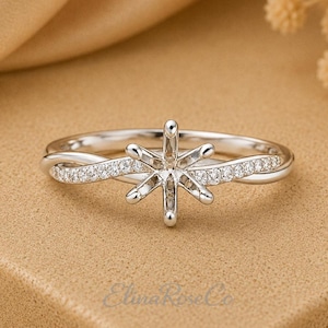 Könnte beinhalten: Ein silberfarbener Ring mit einer sechs-Krappen-Fassung für einen Edelstein. Die Ringschiene ist in einem gedrehten Design gefertigt und mit kleinen, klaren, im Pavé-Stil gefassten Steinen besetzt. Das Metall hat eine polierte Oberfläche.