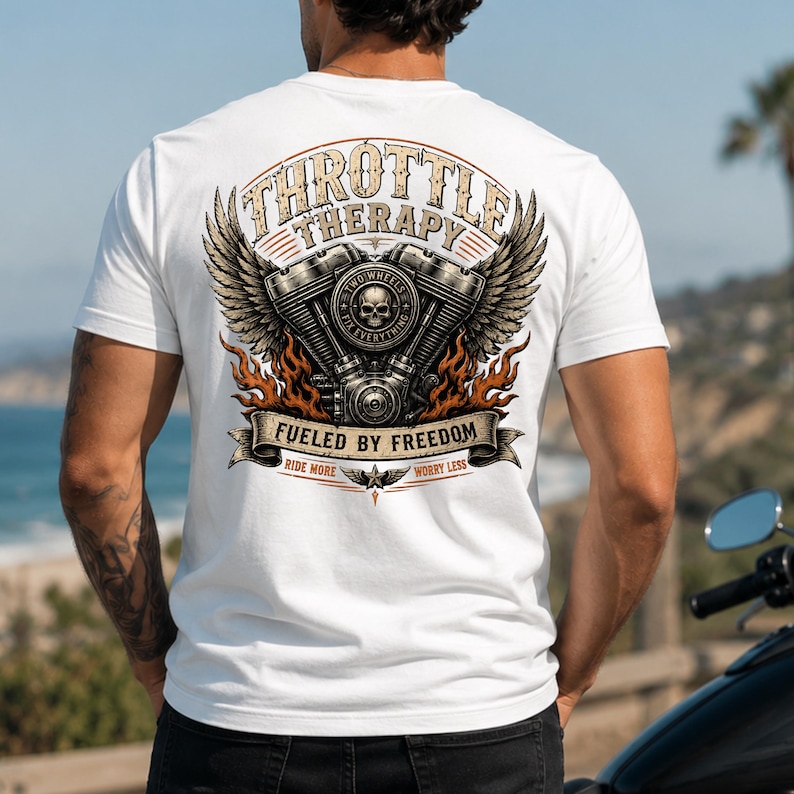 May include: A white short-sleeve t-shirt featuring a back graphic of a motorcycle engine with wings, flames, and a skull. The text reads THROTTLE THERAPY, TWO WHEELS FIX EVERYTHING, FUELED BY FREEDOM, and RIDE MORE WORRY LESS in a decorative font.