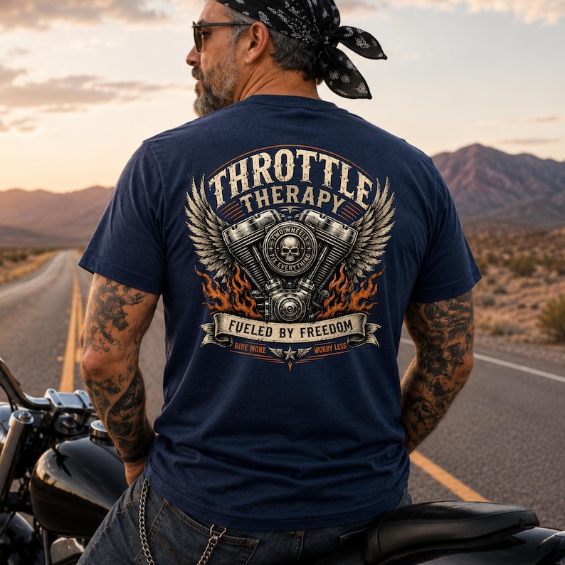 May include: A navy blue t-shirt featuring a graphic on the back with a motorcycle engine, wings, and flames. The text reads "THROTTLE THERAPY," "FUELED BY FREEDOM," "TWO WHEELS FIX EVERYTHING," and "RIDE MORE WORRY LESS" in a stylized, vintage-inspired font.