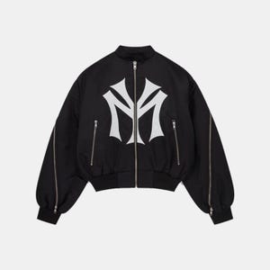 Peut inclure: Veste de bombardier noire avec un logo blanc sur le devant. La veste a une fermeture éclair, deux poches latérales zippées et des fermetures éclair sur les manches. Col et poignets côtelés.