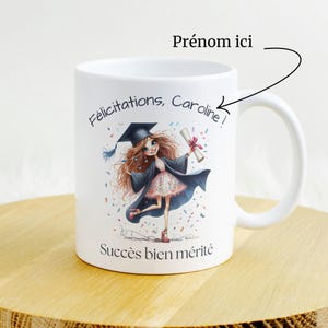 May include: White ceramic mug featuring a graduation illustration of a girl in a cap and gown, holding a diploma. The mug has the text "Félicitations, Caroline!" and "Succès bien mérité".