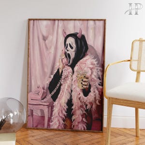 Könnte beinhalten: Ein gerahmter Kunstdruck, der eine Figur mit schwarzer Kapuzenmaske und rosa Teufelshörnern zeigt, die eine rosa Federboa trägt. Die Figur hält ein rosa Wählscheibentelefon und einen Plastikbecher mit einem herzförmigen Strohhalm in der Hand.