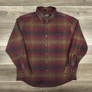 May include: A button-down plaid shirt in shades of burgundy, olive green, and black. The long-sleeved shirt has a button-down collar, a chest pocket, and buttoned cuffs. The Pendleton brand label is visible.